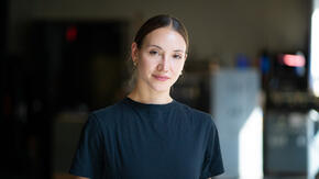 With her hair pulled back and wearing a black t-shirt, Christine Shevchenko looks at the camera for a World Refugee Day 2021 photo shoot,