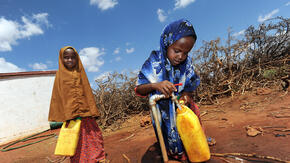 Two girls fill water jugs at an IRC-installed tap in Galkayo, Somalia 