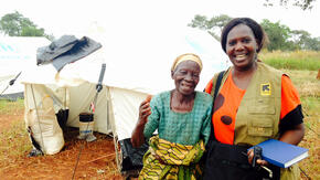 IRC workers poses for photo with elderly Burundian woman in front of tent in Nyaragusu refugee camp in Tanzania.