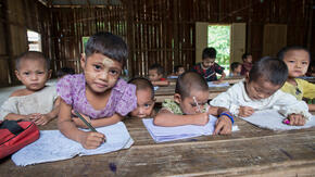 Refugee children hold pencils in a classroom at a refugee camp in northern Thailand