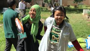 Two students from Burundi and Myanmar hold hands while walking on the lawn outside their school near Atlanta.
