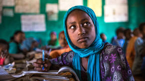 A girl takes notes with a pen and notebook in a classroom in Ethiopia 