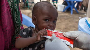 A toddler being treated for malnutrition eats a nutrient-rich peanut butter food