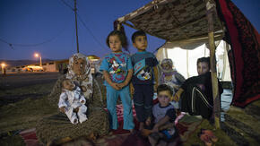 A family made homeless by violence sits outside their makeshift shelter in northern Iraq