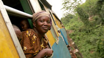 Congolese woman sticking head out of moving railroad car en route to market.