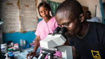Health workers test for the Ebola virus. Photo: T. Trenchard/Panos An IRC health worker testing for the Ebola virus examines a sample on slide on a microscope