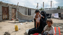 A mother and her two young children seated outdoors in Yemen