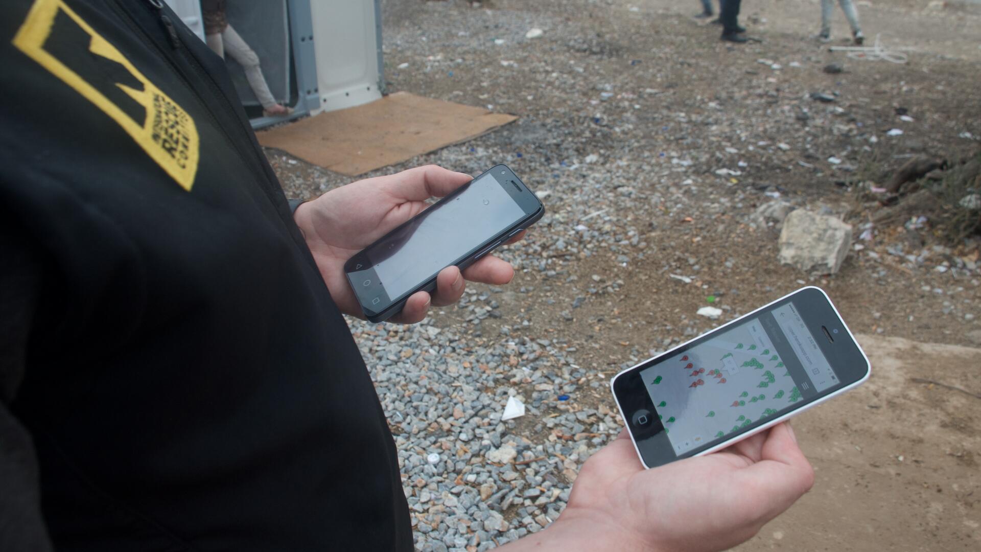 An IRC aid worker in Greece looks at an IRC  shelter mapping app on a smartphone
