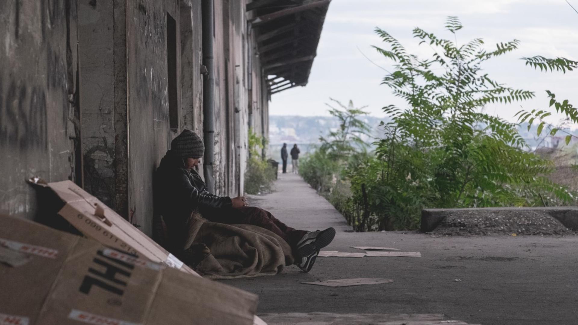 A young Afghan refugee sits huddled outside an abandoned warehouse in Serbia.