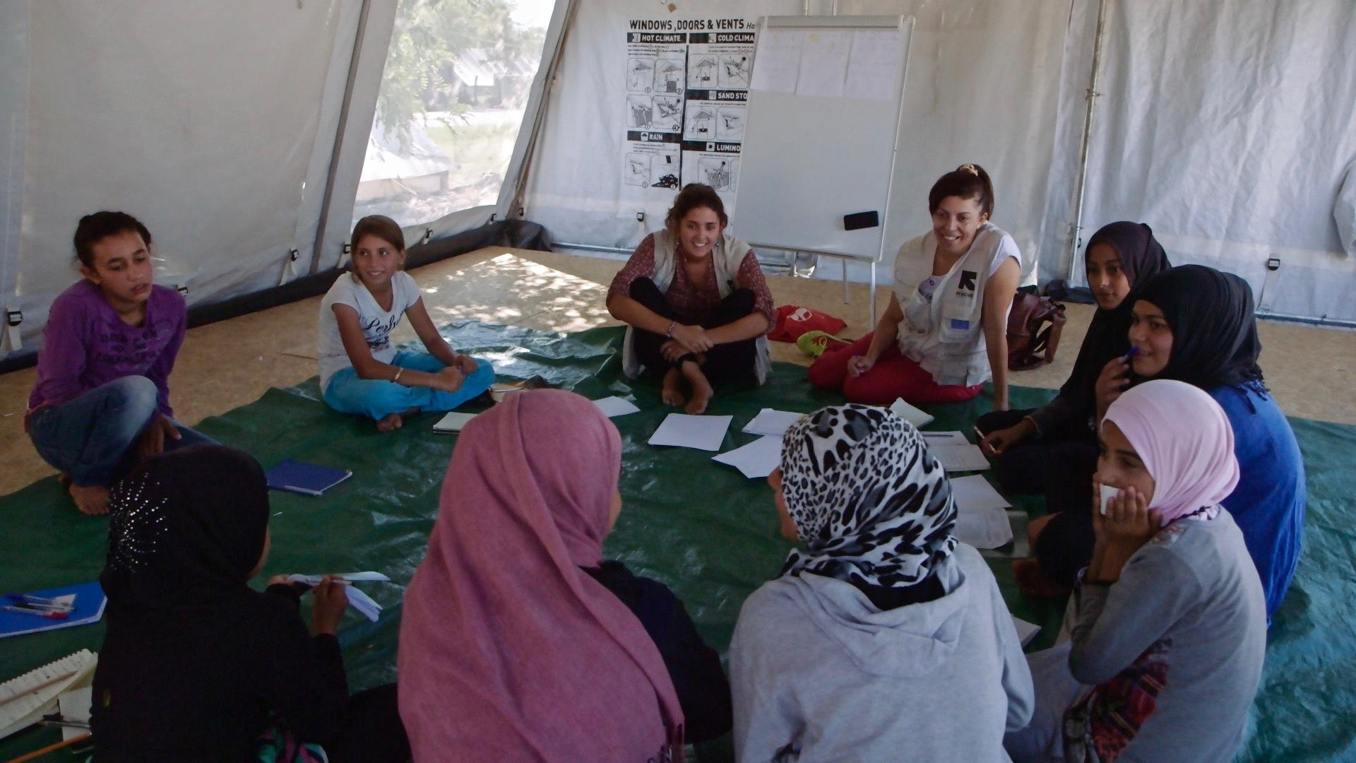 Refugee girls play games in a tent that serves as an IRC "safe space" in a camp in Greece