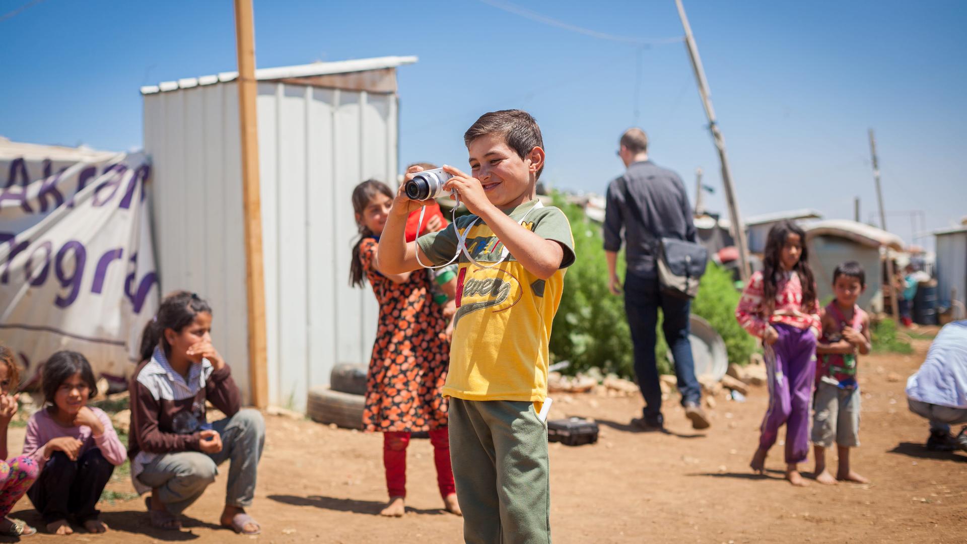 Maher, a Syrian boy, takes photographs of his friends in a refugee camp in Lebanon