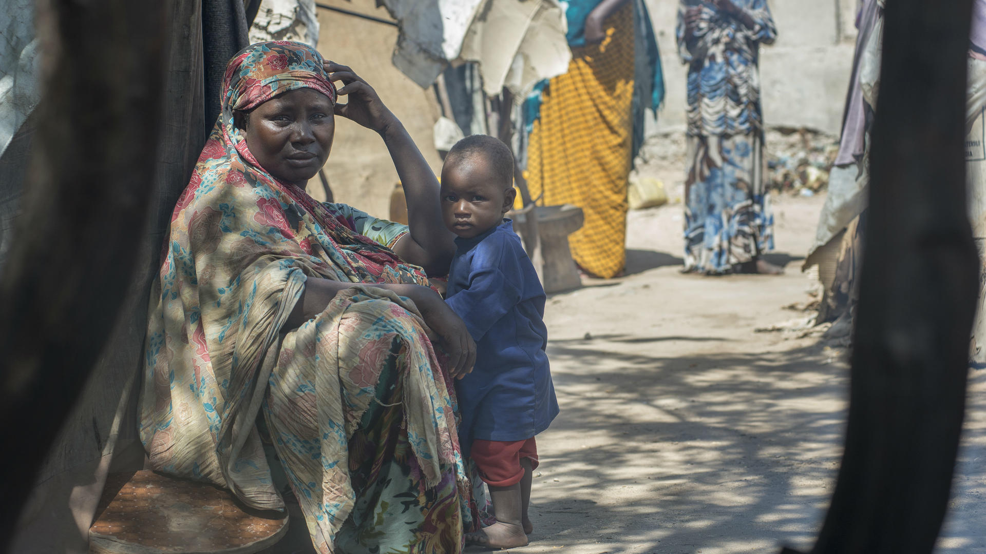 Displaced woman and child, Mogadishu, Somalia. Photo: Peter Biro/IRC Displaced woman sits with a child outside a tent in Mogadishu