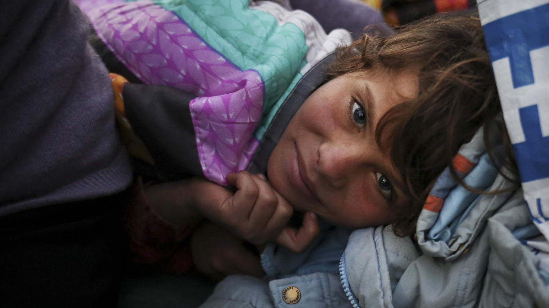Nadia, age 7, a Syrian refugee from Kobani, Syria, stays warm with her family at sunrise, at the Moria refugee camp, in Mytilene, on the island of Lesbos, Greece A Syrian refugee girl napping inside a tent in Greece