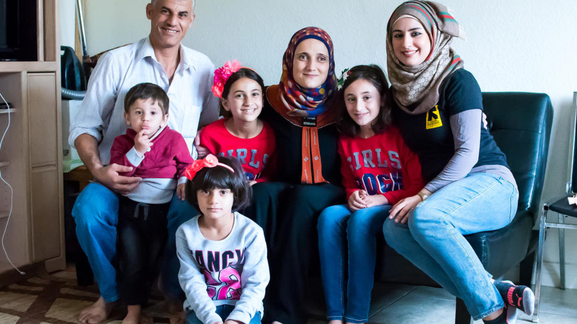 The Tlas family, refugees from Syria, pose for a photo with an IRC staff member in their new home in San Diego 