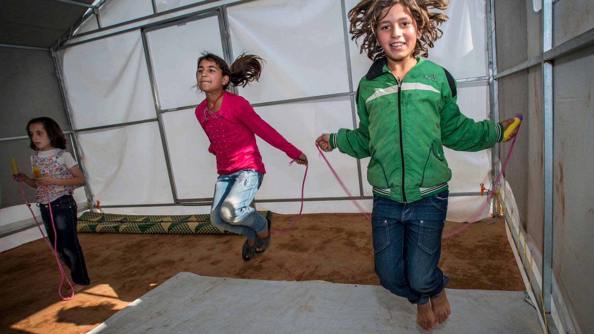 Two girls jump rope in a temporary classroom  in Idlib. 