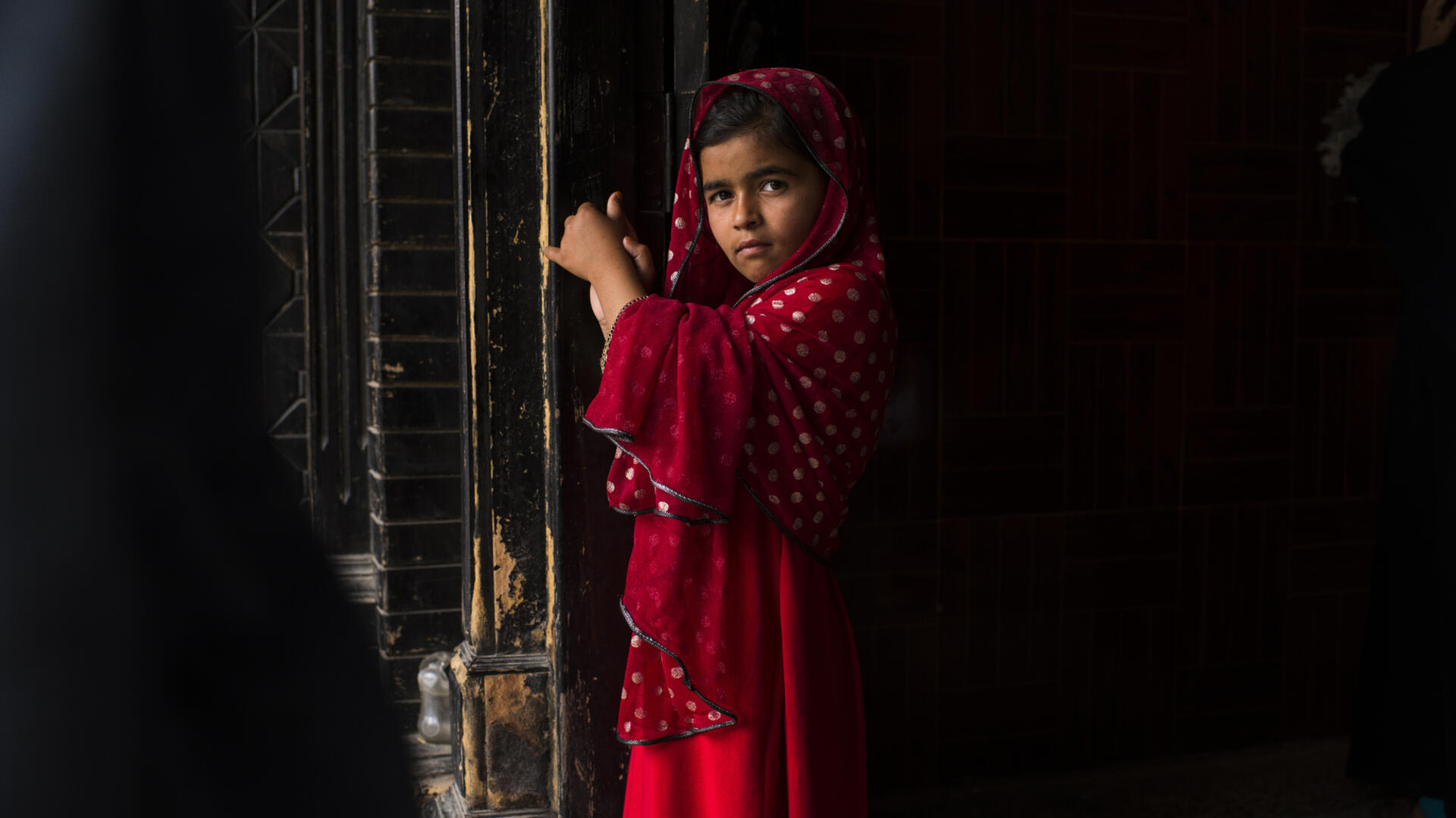 A young girl waits while her family -- Afghan refugees forced to return from Pakistan -- receive emergency cash and relief supplies from the International Rescue Committee in Jalalabad, the capital of Afghanistan's Nangarhar province. A young Afghan girl in Jalalabad