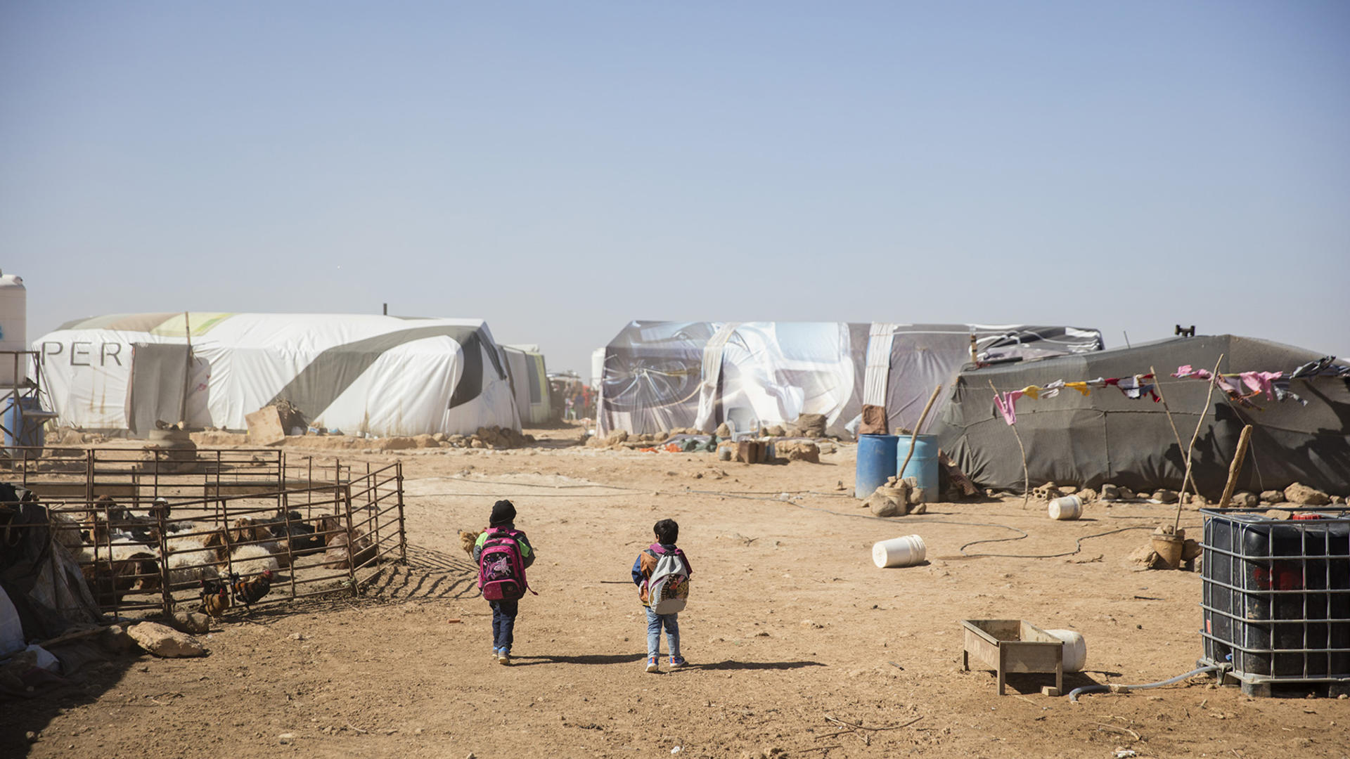 Syrian children walk through rows of tents in a refugee camp in Jordan