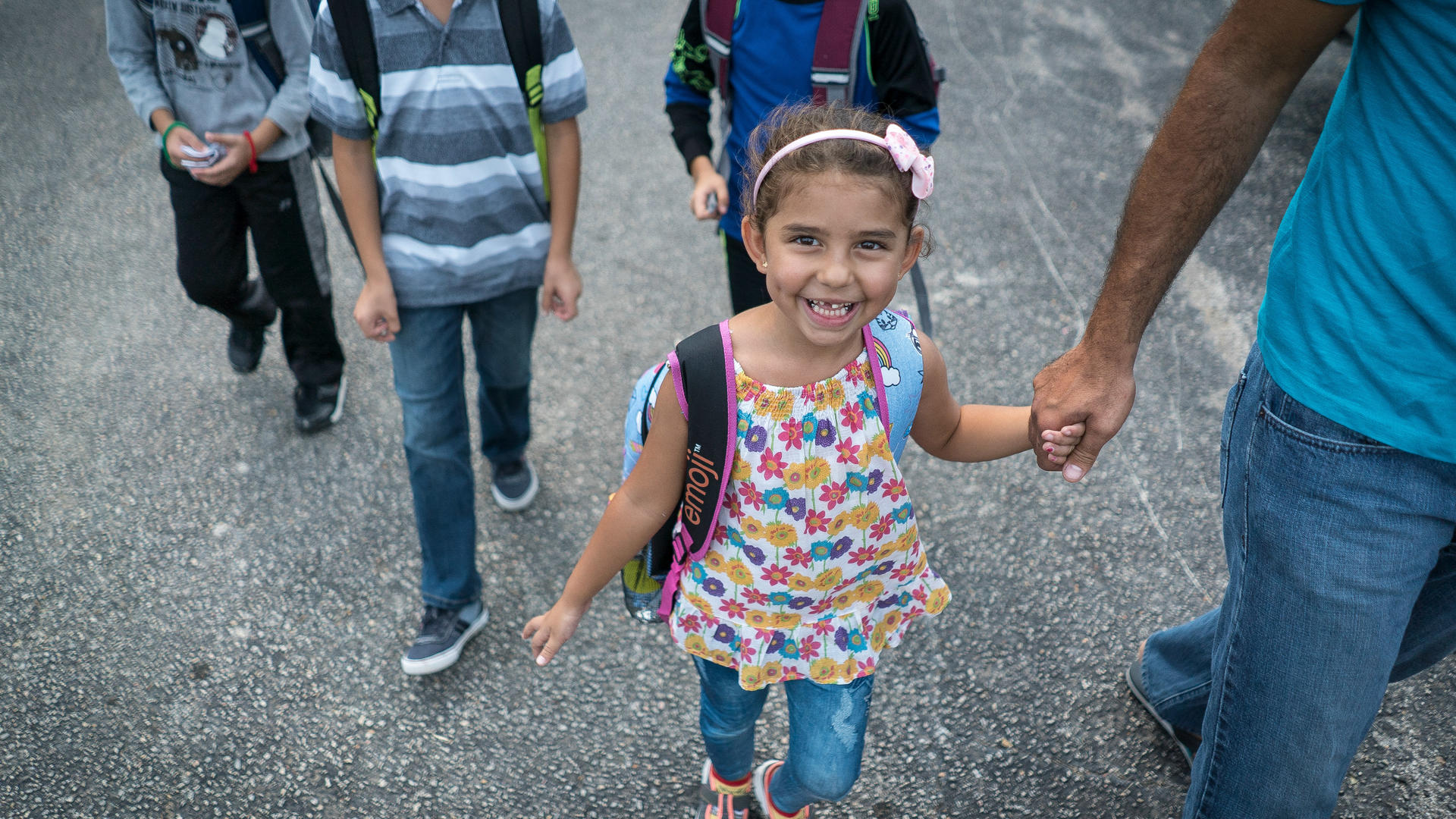 Jori walks to school with her parents during her first week of kindergarten. Jori holds her father's hand while walking to school