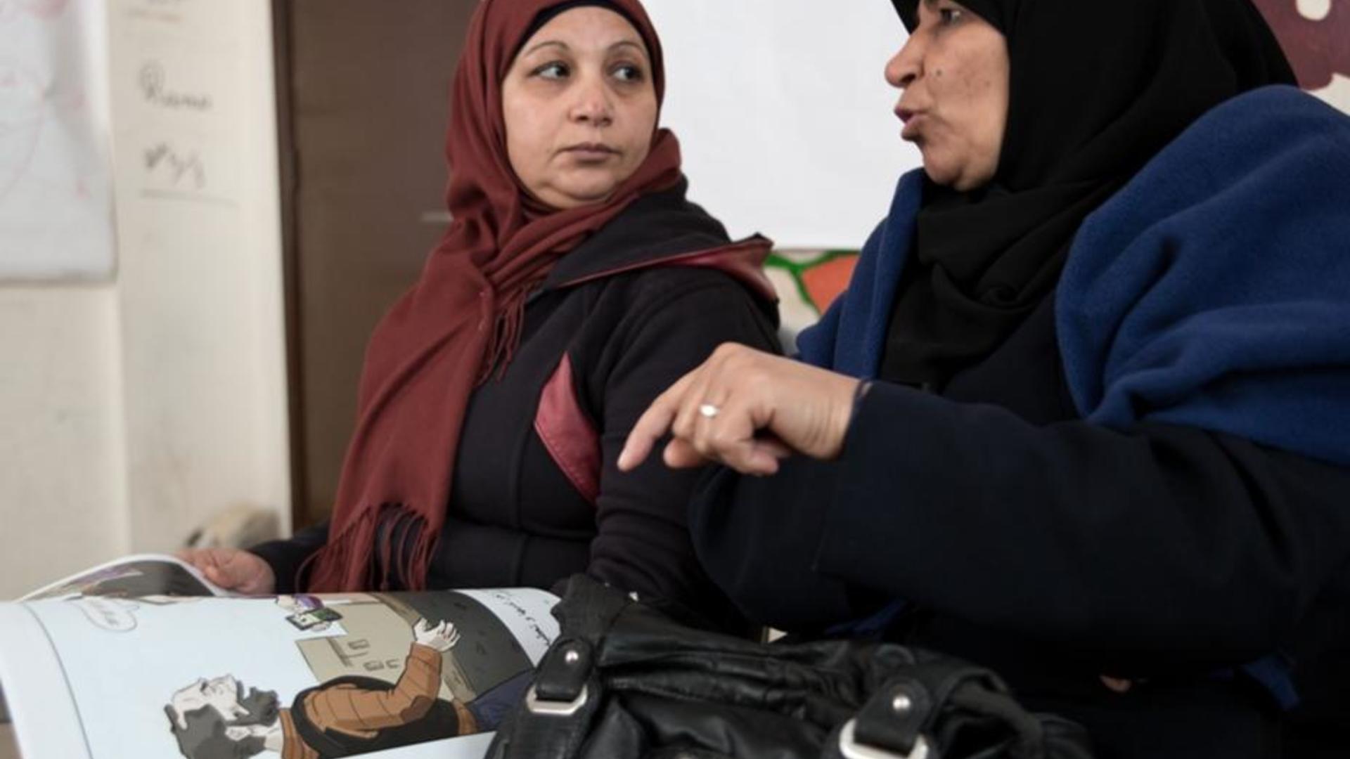 Syrian women look at an IRC-created comic book and discuss decisions the main character makes