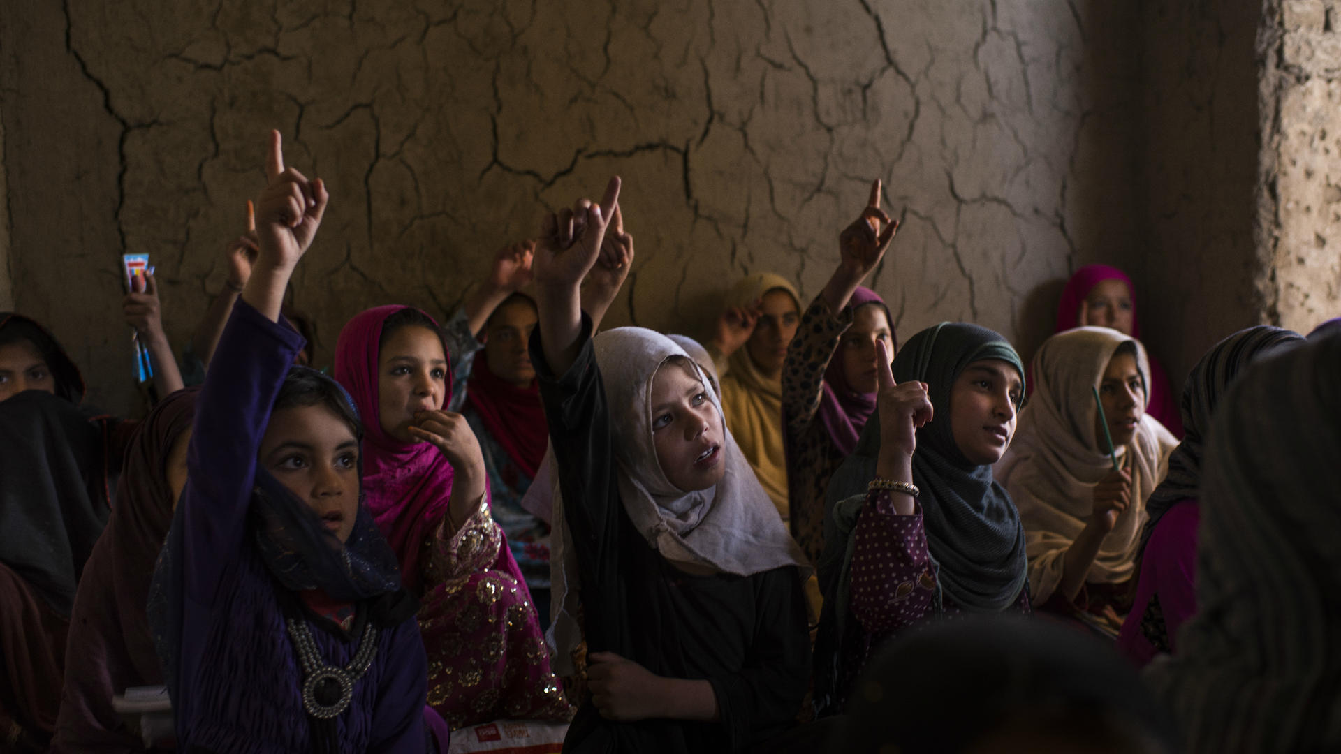 Girls raise their hands in an IRC-supported community school classroom in Afghanistan Girls raise their hands in a primary school classroom in Afghanistan