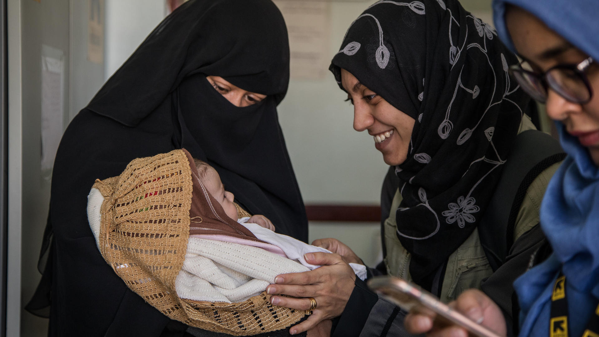 New mother Mona Mohammed (left) brings her children to an IRC-supported health clinic in Sana'a, Yemen New mother Mona Mohammed shows her baby to IRC health workers at a clinic in Sana'a