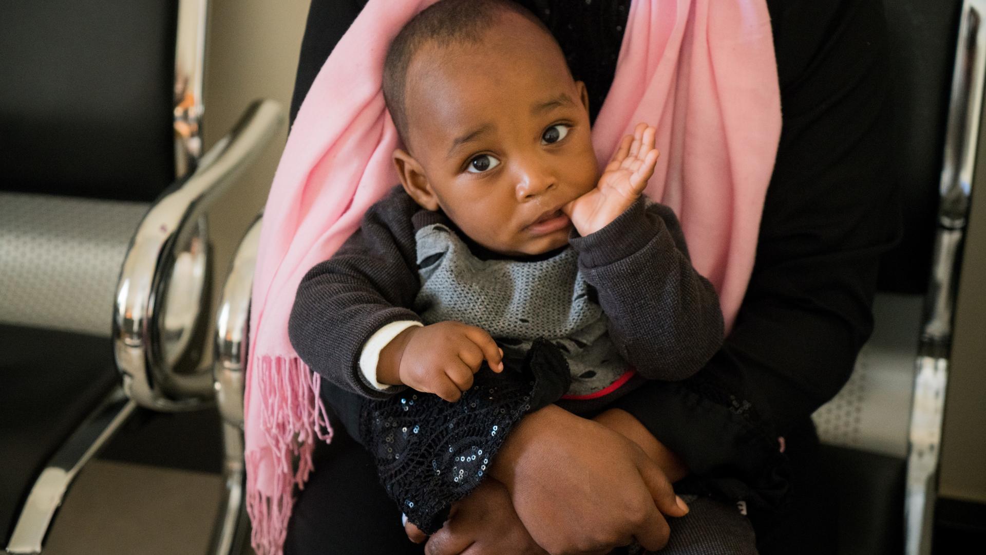 Khal, a 10-month-old boy from Eritrea, sits on his mother's lap in the Community Development Center in Tripoli, Libya