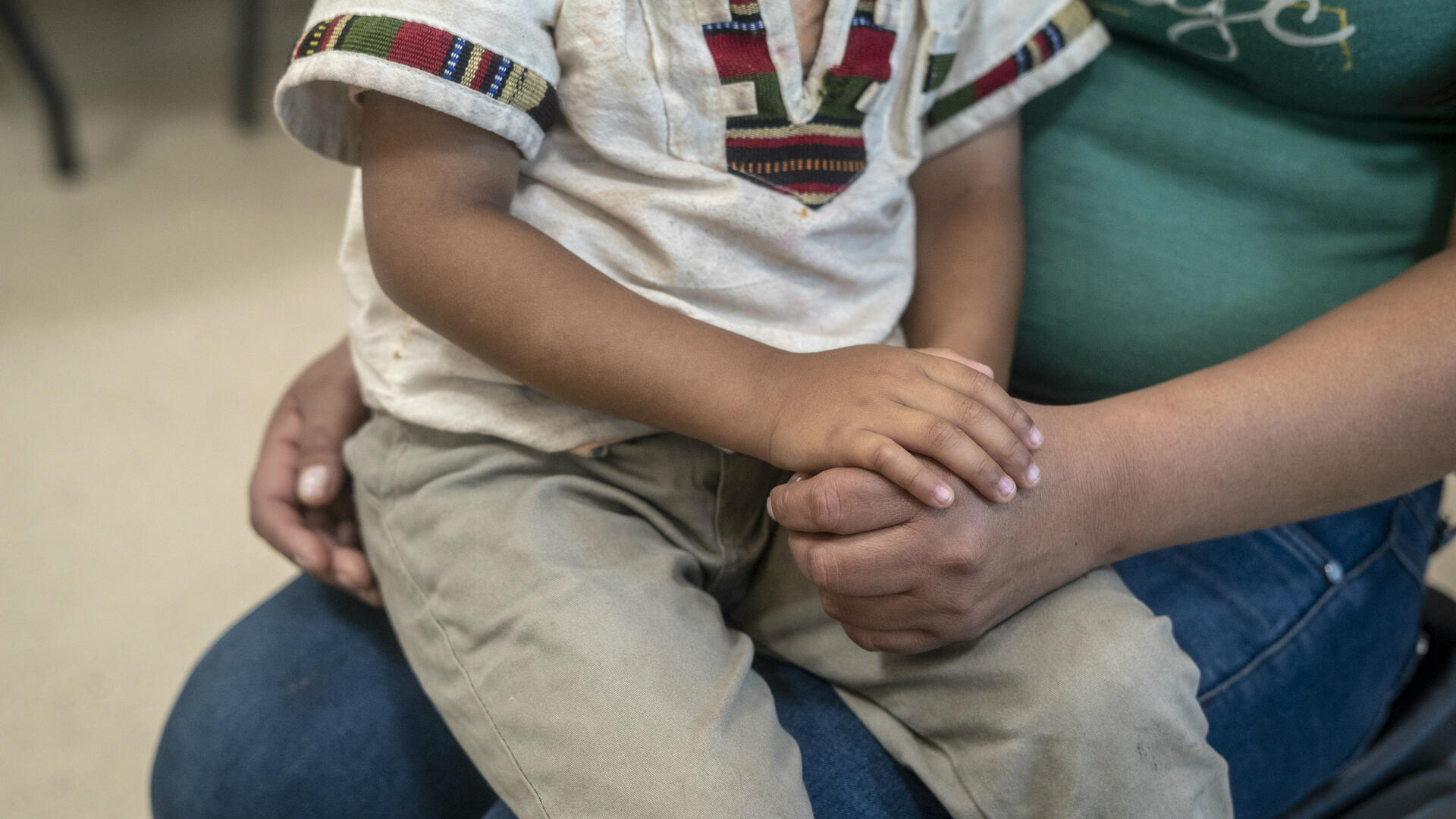 A Central American child sits on his mother's lap at an IRC day center for asylum seekers in Arizona