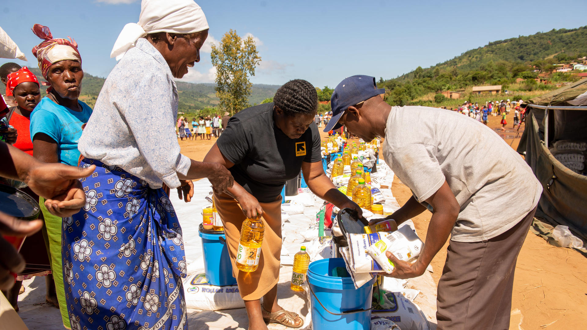 A woman collects food and emergency aid from IRC staff in Zimbabwe after Cyclone Idai