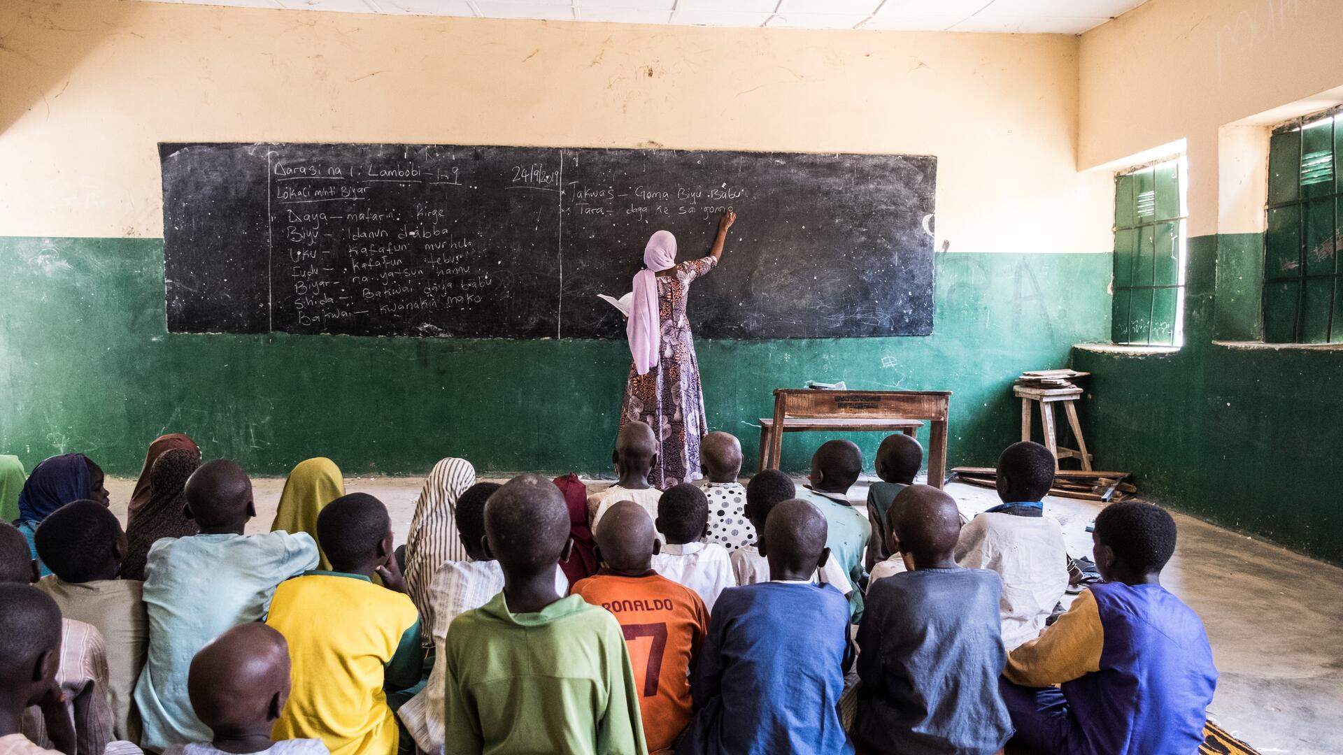 International Rescue Committee teacher Fatima writes on a blackboard in the front of her classroom.