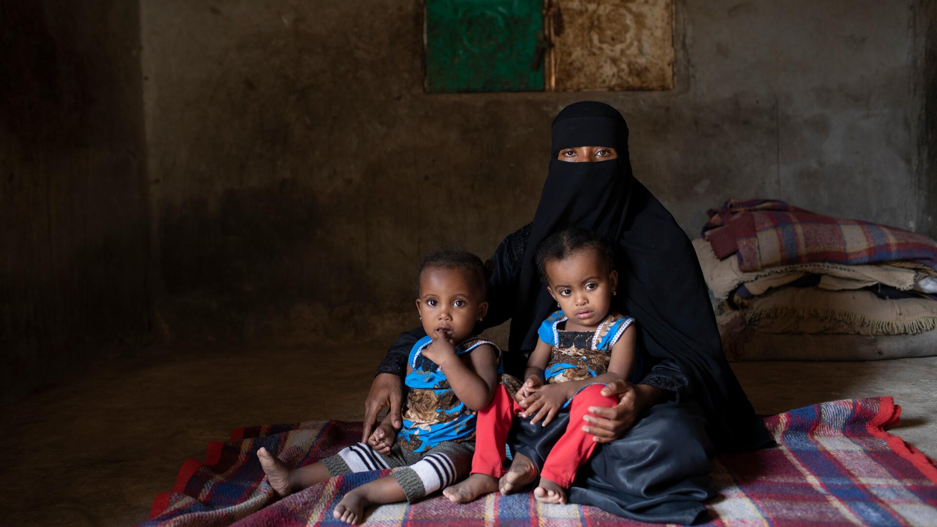 A mother in Yemen sits with her twin daughters