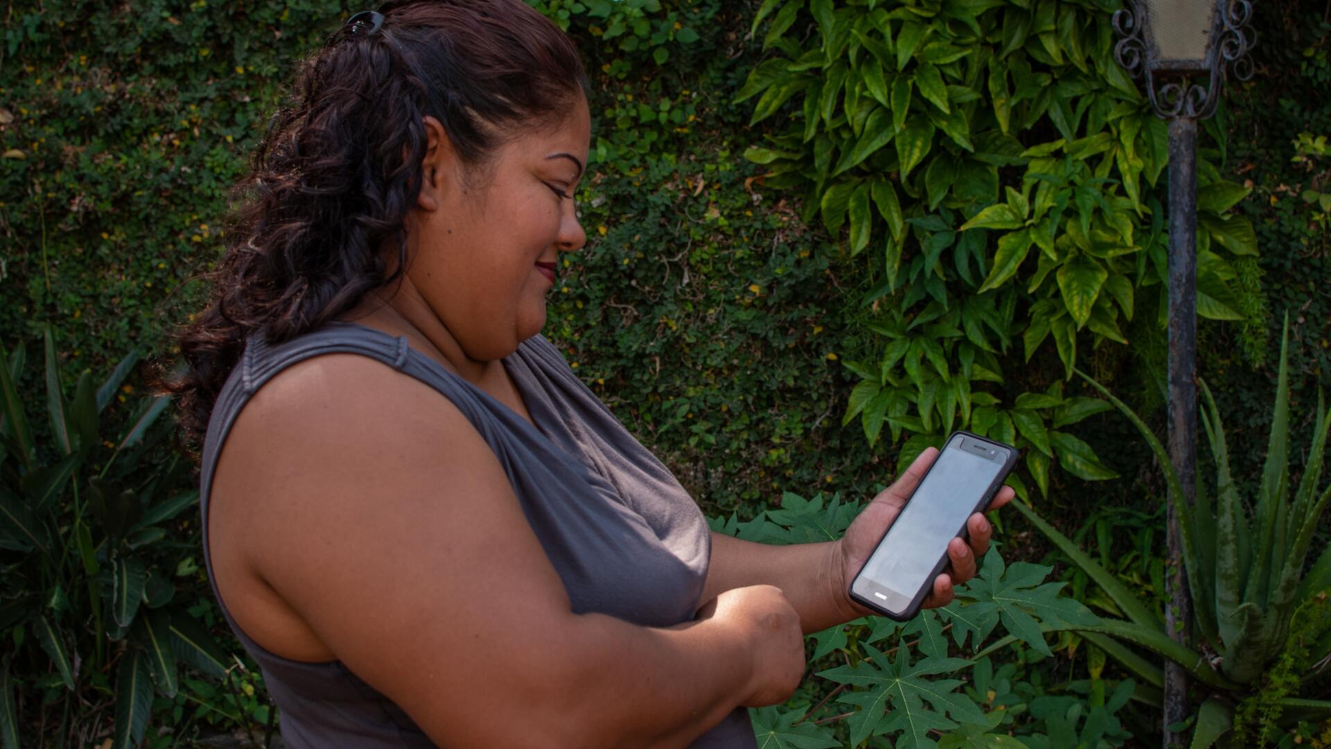 A woman in El Salvador who has received support from the IRC and CuentaNos looks at her cellphone