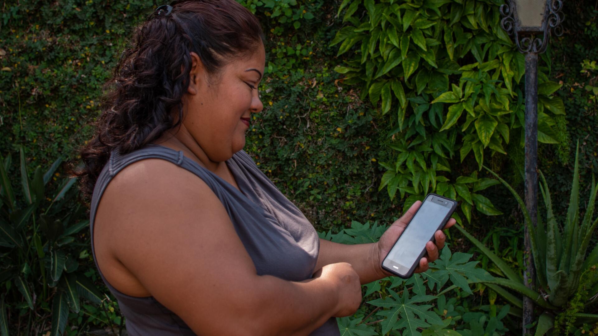 A woman in El Salvador who has received support from the IRC and CuentaNos looks at her phone A woman in El Salvador who has received support from the IRC and CuentaNos looks at her cellphone