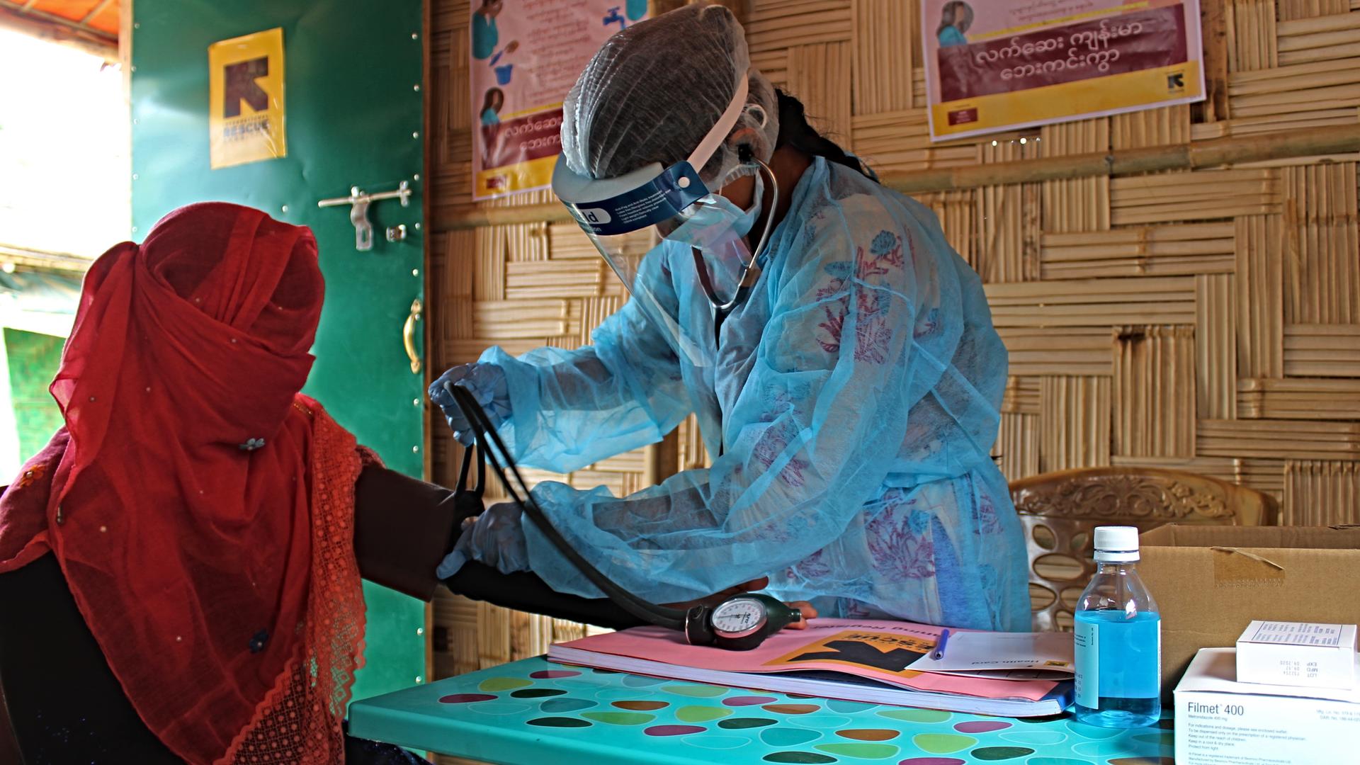 An International Rescue Committee midwife donned protective gear to give a patient in a Bangladesh refugee camp her regular checkup during the coronavirus pandemic. An IRC midwife in Bangladesh, wearing a mask, face shield and protective suit, reads the blood pressure of a patient whose face is covered by a veil to guard against COVID-19.