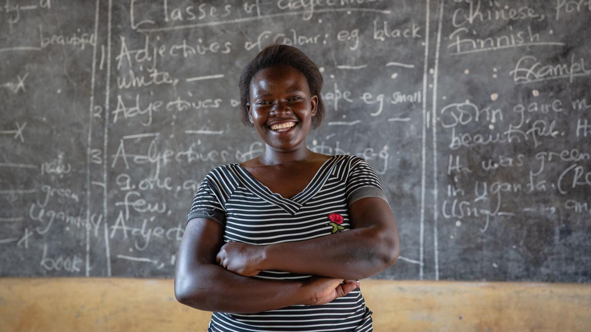 Jackie Letaru, a teacher and activist in Uganda Jackie Letaru, a teacher and activist in Uganda, poses smiling in front of a chalkboard