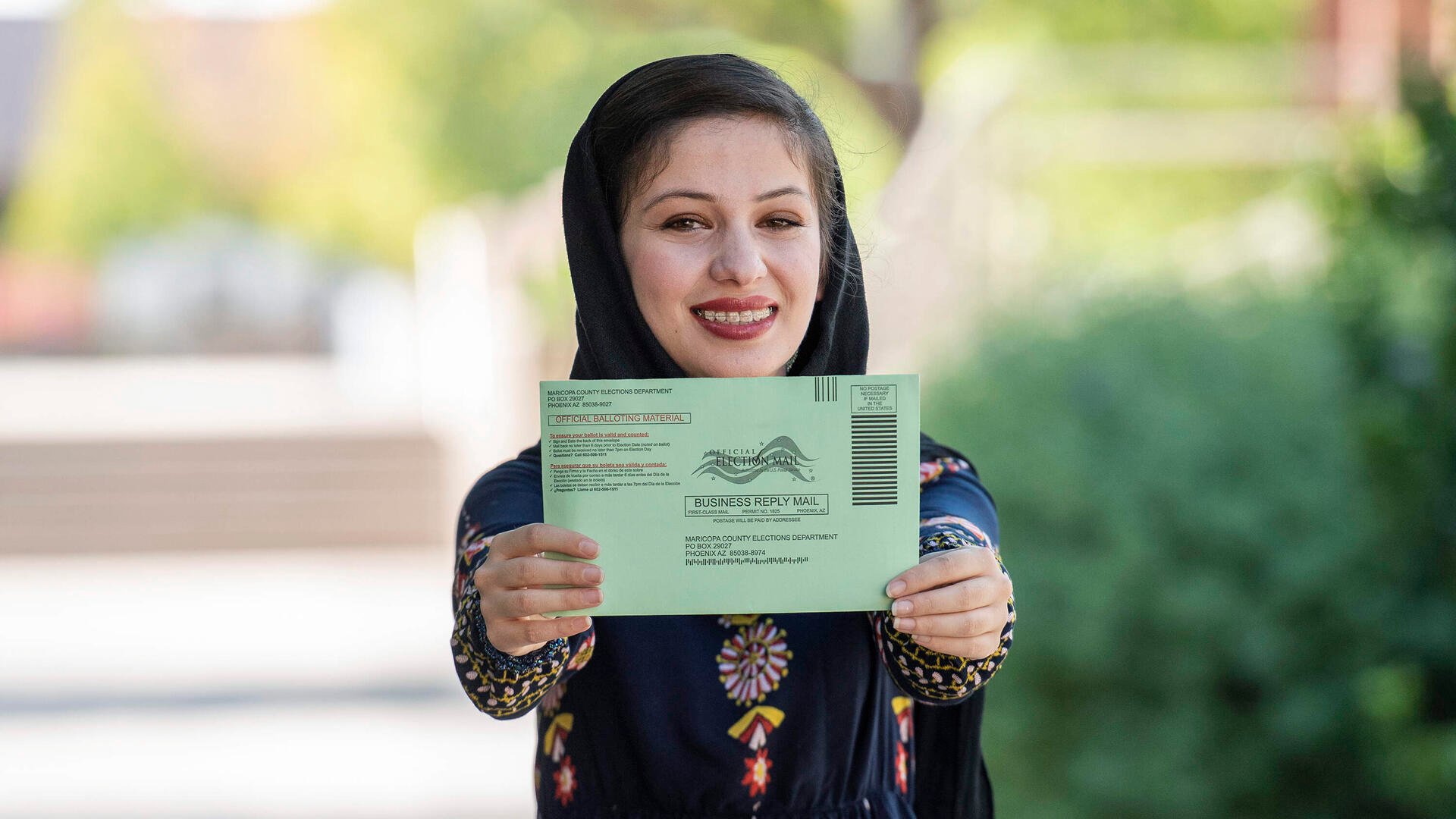 Muska Haseeb holds out her mail-in ballot 
