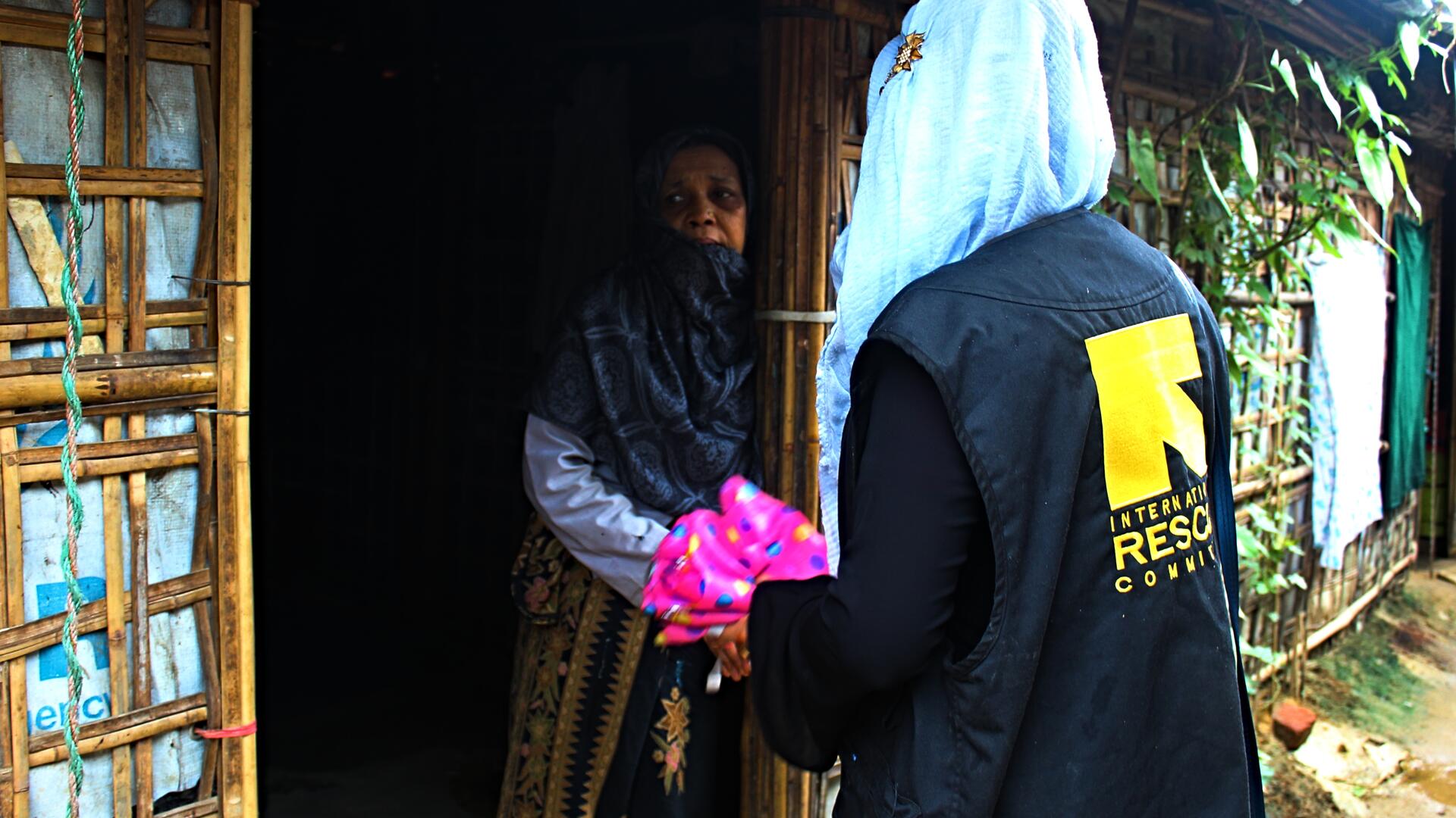 An IRC community health worker and refugee from Myanmar visits a woman in a refugee camp in Bangladesh with information about COVID-19.