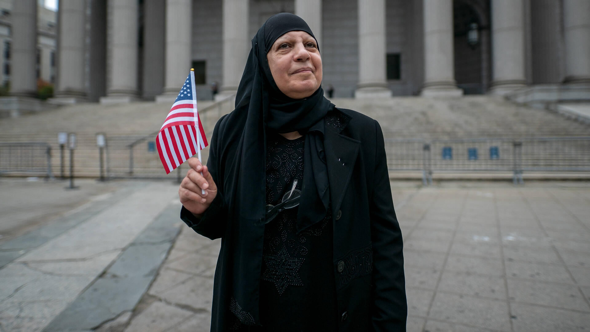 Maha celebrates her citizenship Maha al-Obaidi stands in front of a government building holding an American flag.