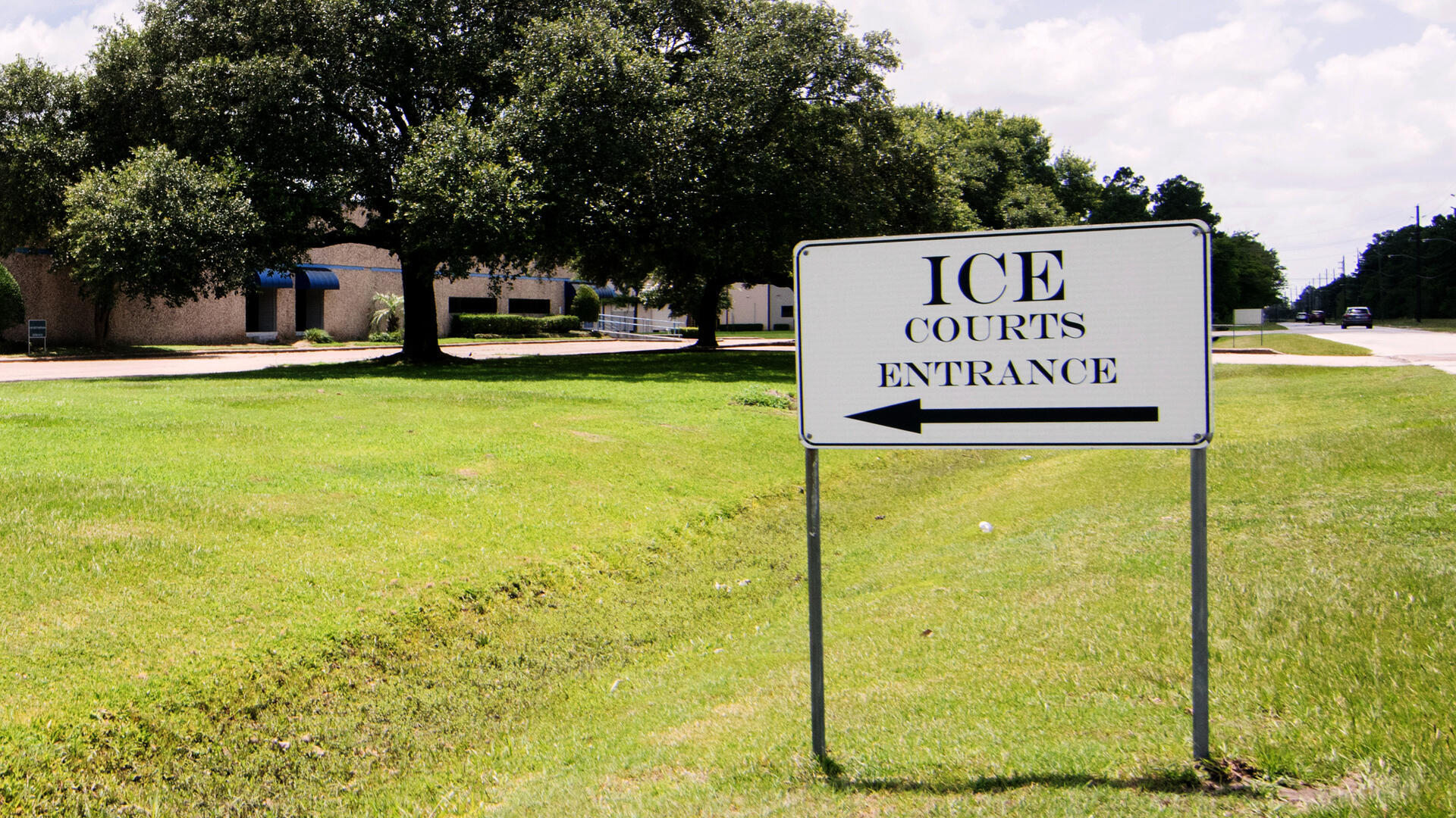 A sign outside an immigration court A lawn with a black and white sign that says "ICE Courts Entrance"