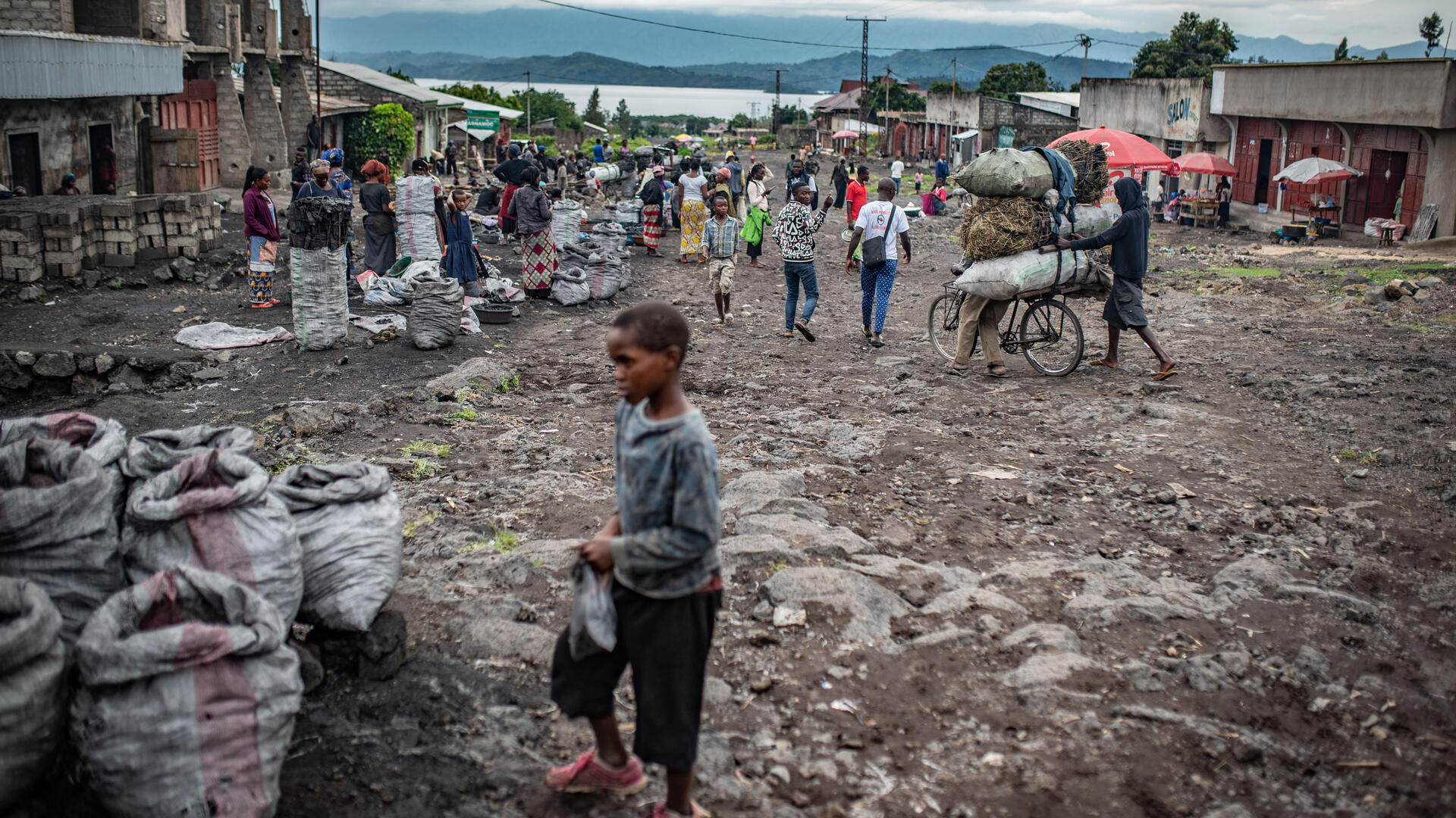 A boy in Goma, Democratic Republic of Congo. The city is threatened by yet another eruption of the Mt. Nyiragongo volcano. A young boy and other people on the street in Goma, DRC on a cloudy day