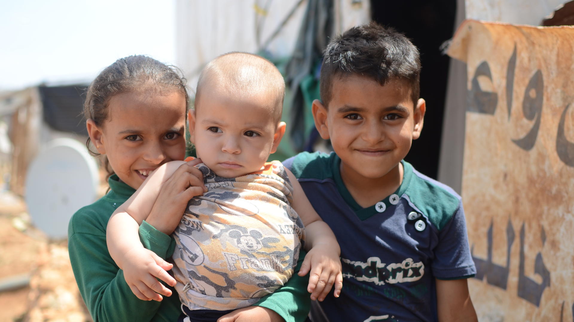 Syrian children in a refugee settlement in Lebanon Two Syrian children hold a baby outside a tent in a refugee settlement in Lebanon