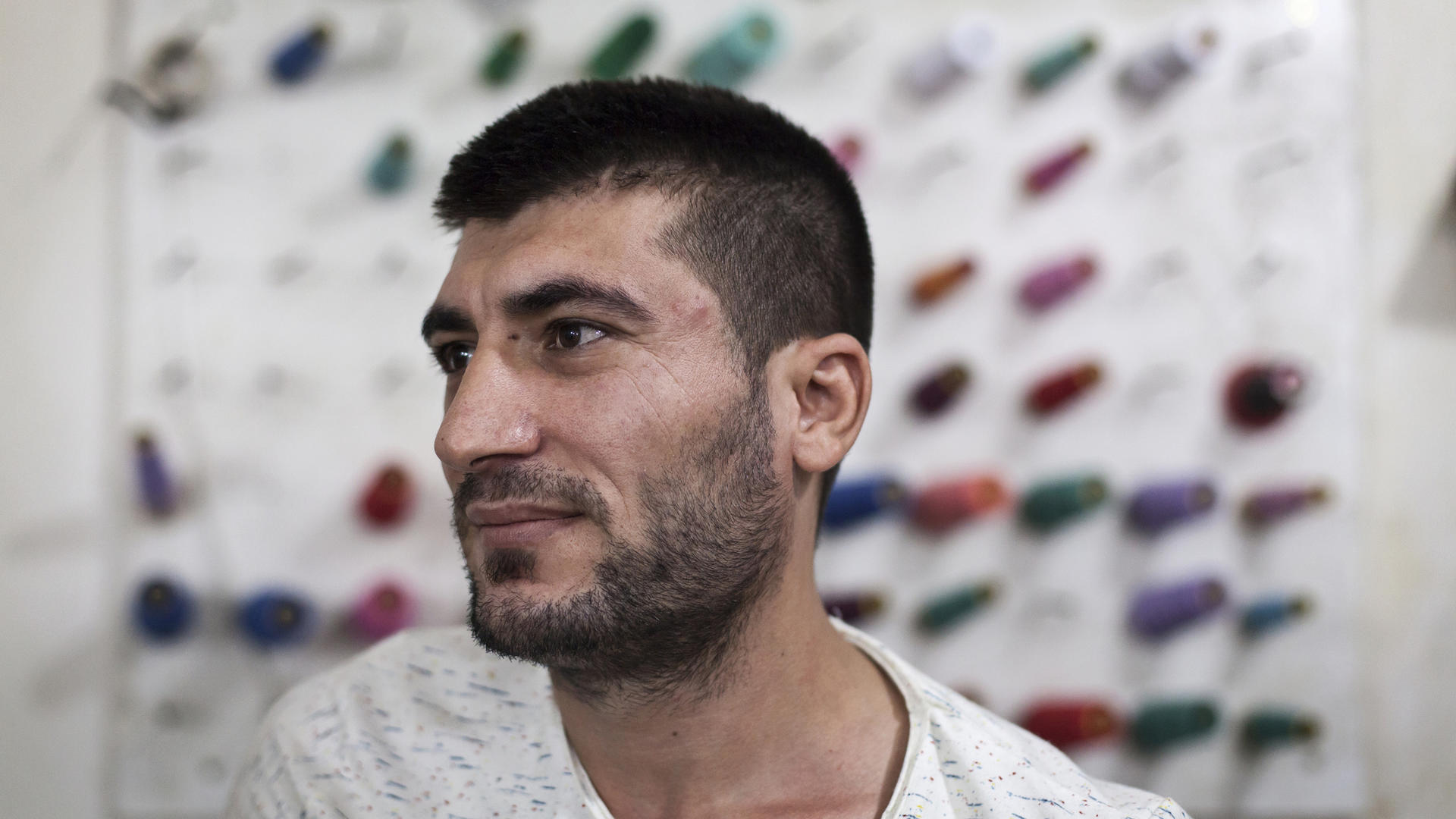Mohamed Saleh Ismail stands in front of reels of thread in a tailoring workshop in Lebanon