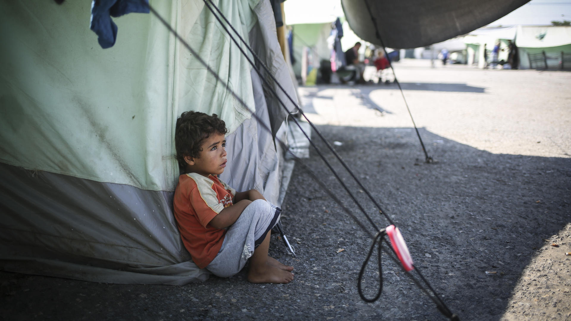 A little boy sits in the shade to escape the mid-day sun at the Alexandria refugee camp in northern Greece