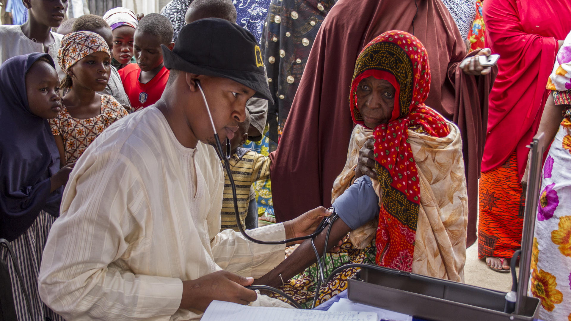 An IRC health worker checks an elderly woman's blood pressure