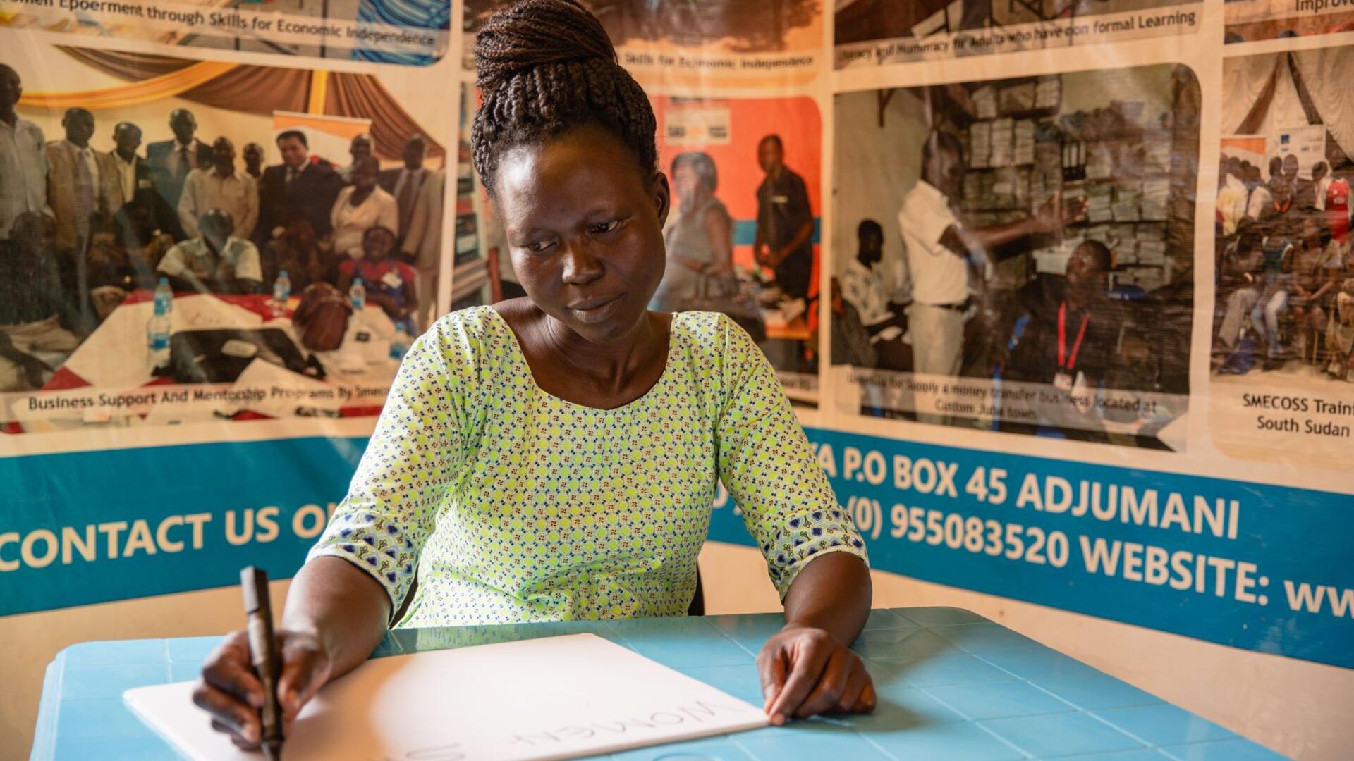 Grace sits at a desk in her office writing on a piece of paper.