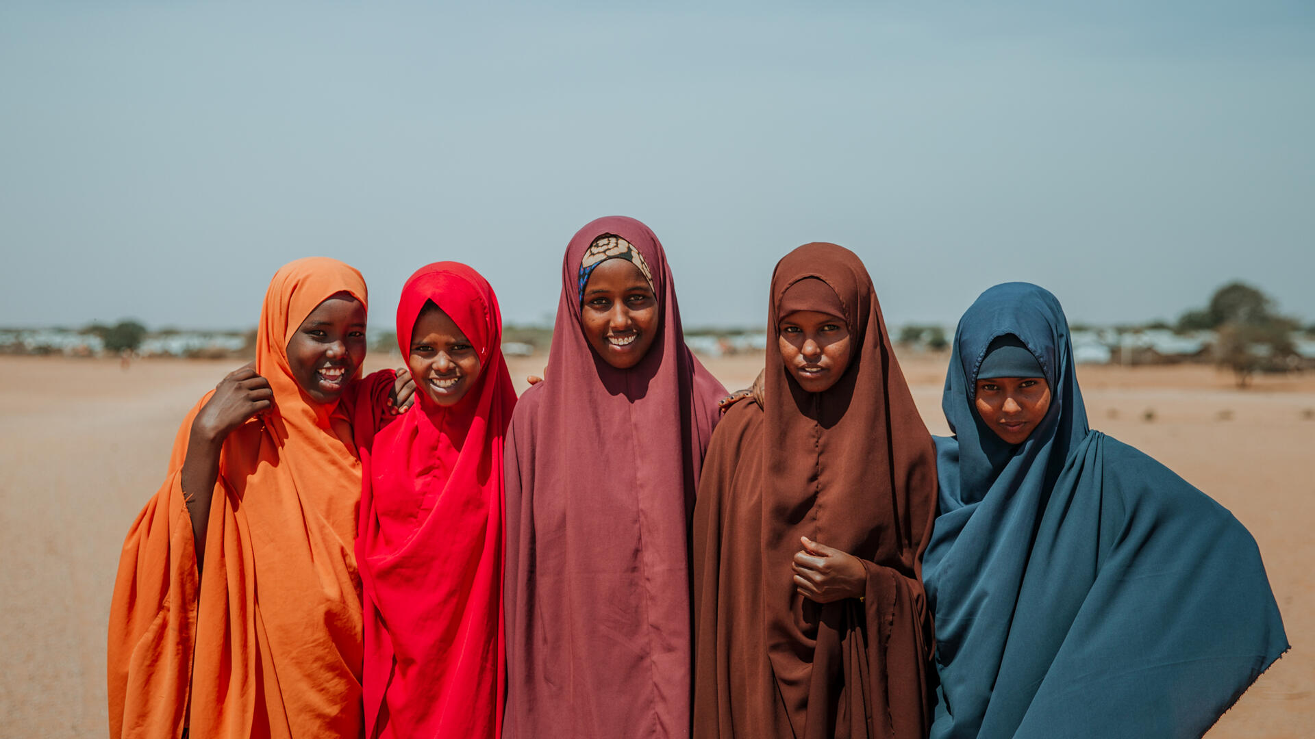 Five girls who are part of the IRC's Girl Shine program -- Ampia, Asha, Hibo, Shamsa, and Nurta --stand together for a photo in a dry landscape in Ethiopia.