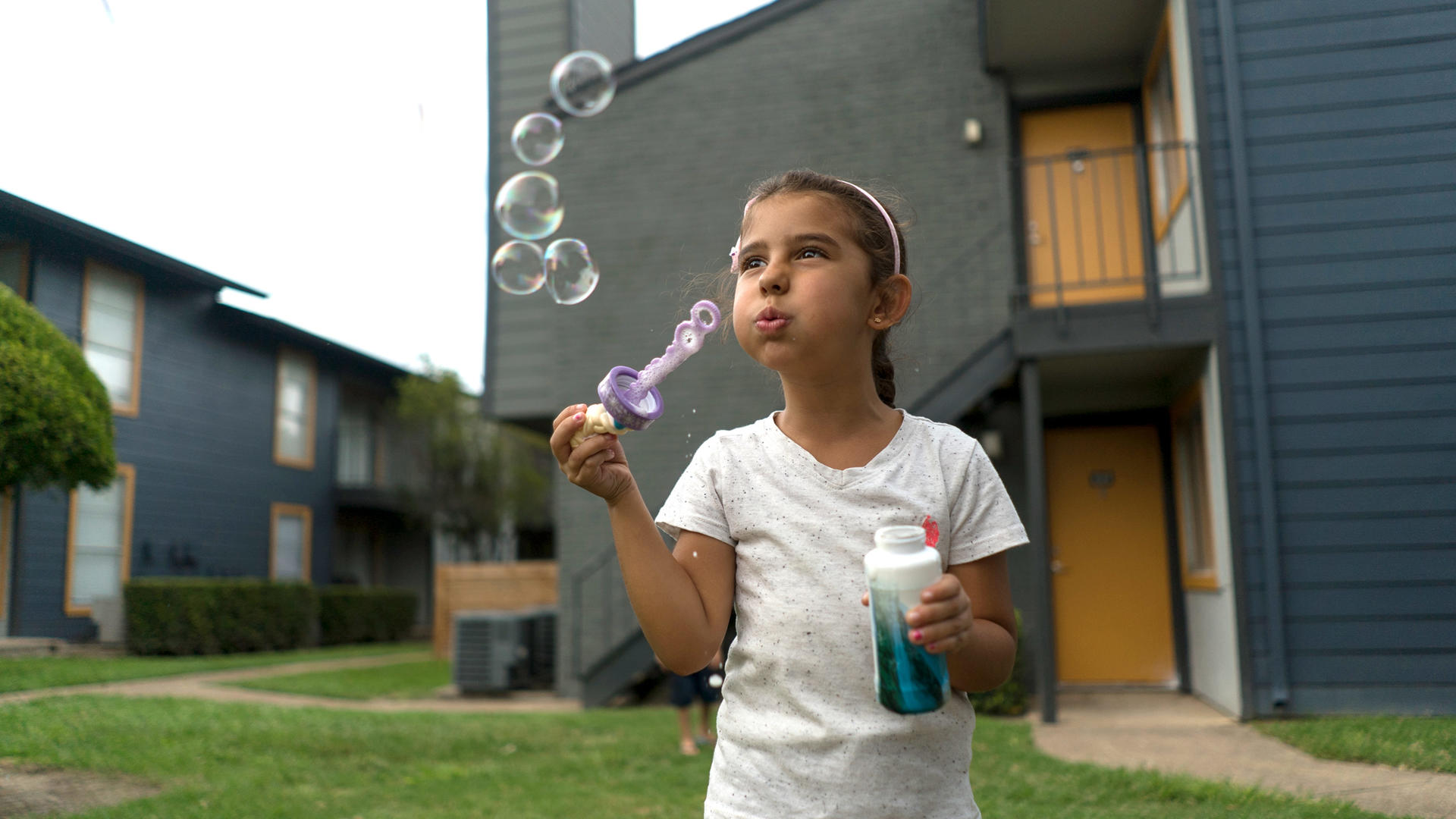 Jori blows bubbles outside her family's apartment