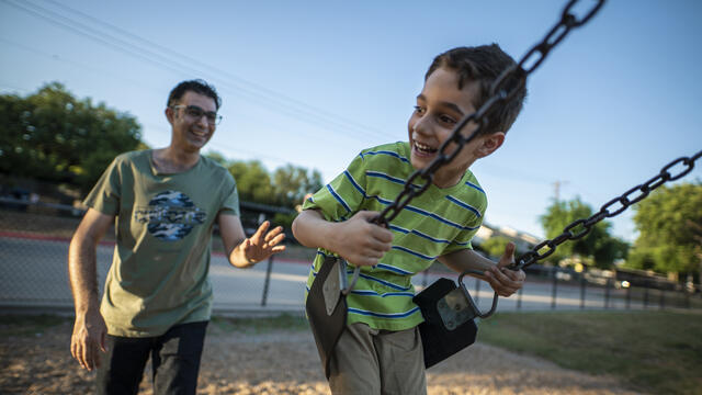 A father, Junaid, pushes his son Ridha on a swing in a playground in Dallas. The family arrived in the U.S. as refugees.